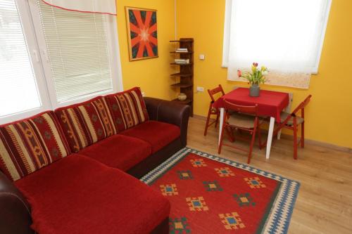 a living room with a red couch and a table at Apartments Life & Energy in Čatež ob Savi