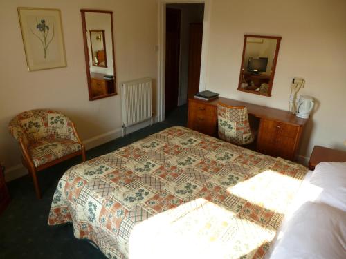 a bedroom with a bed and a dresser and mirror at Somerton House Hotel in Lockerbie