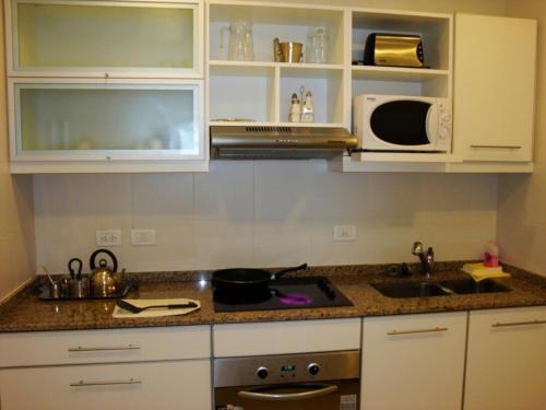 a kitchen with white cabinets and a sink and a microwave at Cariló Sul Mare in Carilo
