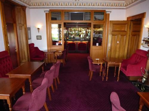 a restaurant with tables and chairs and a bar at Somerton House Hotel in Lockerbie