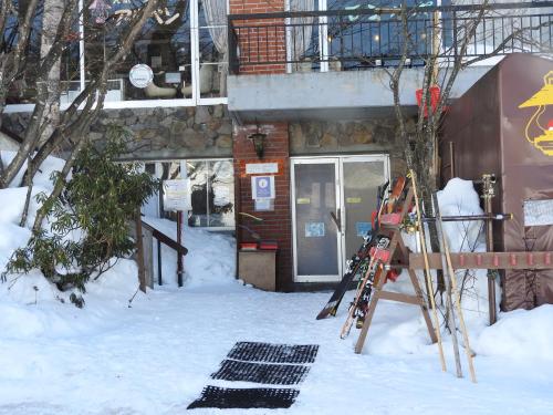 un par de esquís en la nieve frente a un edificio en Villa Alpen, en Yamanouchi