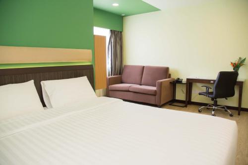 1 dormitorio con cama, silla y escritorio en The Capital Residence Suites, en Bandar Seri Begawan