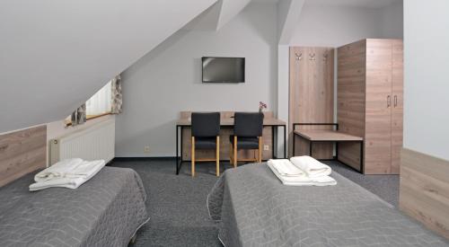 a bedroom with two beds and a table with chairs at Zajazd Aleksandria in Aleksandrów Łódzki