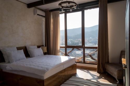 a bedroom with a bed and a large window at Golden Fleece in Mtskheta
