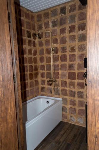 a bath tub in a bathroom with a brick wall at Golden Fleece in Mtskheta