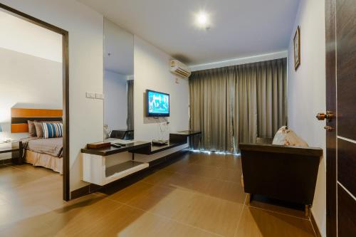 a hotel room with a bed and a television at Vogue Pattaya Hotel in Pattaya Central