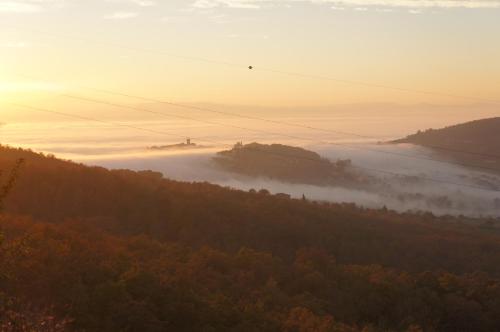 a view of a foggy valley with trees and the sun setting at EcoResort Il Cantico della Natura in Magione