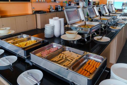 a buffet line with trays of food and plates at Vogue Pattaya Hotel in Pattaya Central