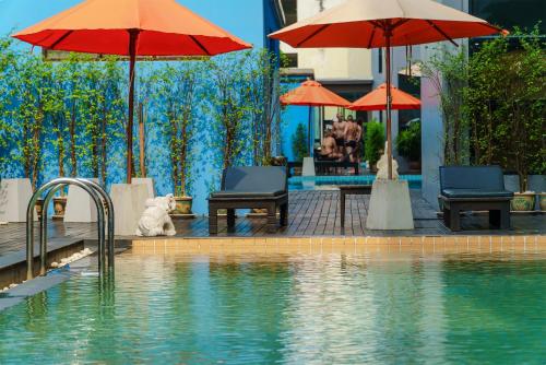a pool with umbrellas and chairs and a teddy bear sitting next to at Vogue Pattaya Hotel in Pattaya Central