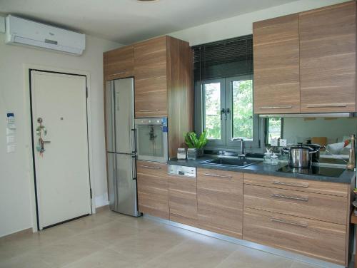 a kitchen with wooden cabinets and a stainless steel refrigerator at Luxury Villas 1 in Synoikismós Panteleímonos
