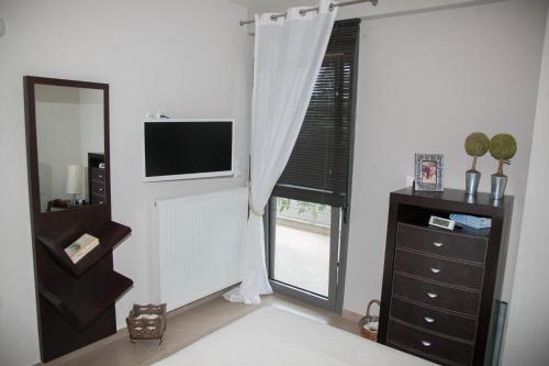 a living room with a television and a window at Luxury Villas 1 in Synoikismós Panteleímonos