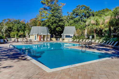 a swimming pool with chairs and a house at Evian 154 in Hilton Head Island