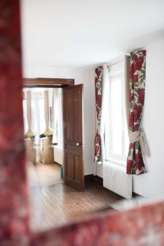 Cette chambre dispose d'une porte et de fenêtres avec des rideaux. dans l'établissement Le Tout à Pied et son parking privé, à Étretat