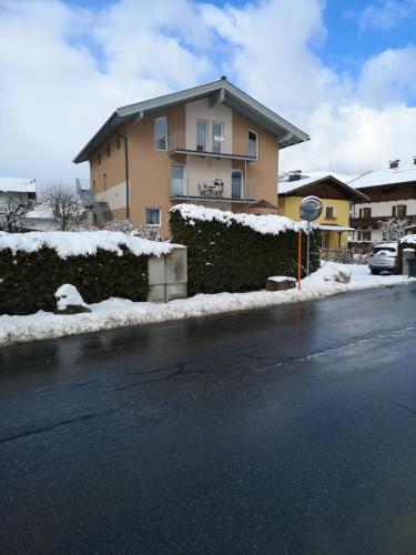 a house with snow on the side of a street at Appartement Petra in Bruck an der Großglocknerstraße