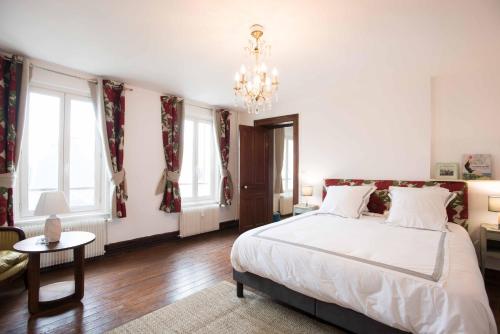 a bedroom with a large white bed and a chandelier at Le Tout à Pied et son parking privé in Étretat
