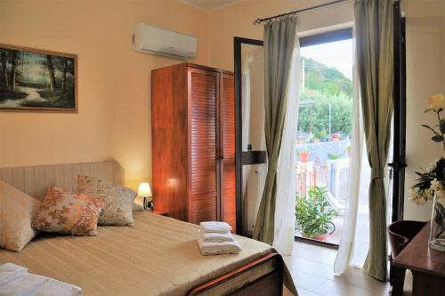 サーヴォカにあるIl Belvedere vicino Taorminaのベッドルーム1室(ベッド1台付)、バルコニーへのドアが備わります。