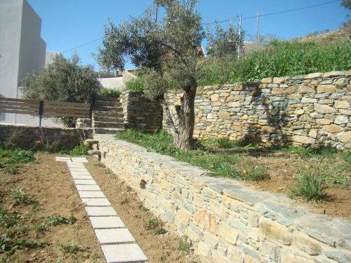 a stone wall with a tree and a bench at Vrahos Agios Romanos in Agios Romanos