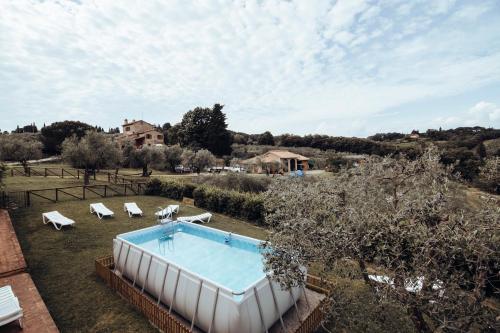 a pool in a yard with chairs and a house at Agriturismo Il Pintello in San Casciano in Val di Pesa