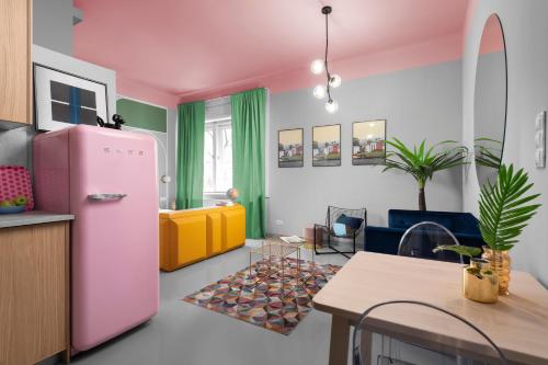 ブダペストにあるLucifer Apartmentのピンクの冷蔵庫とテーブル付きのキッチンが備わります。