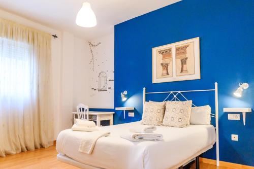 a blue bedroom with a bed and a blue wall at Apartamentos Turísticos Architettura Úbeda in Úbeda