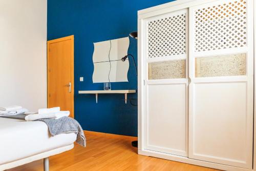 a room with a white wardrobe and a blue wall at Apartamentos Turísticos Architettura Úbeda in Úbeda