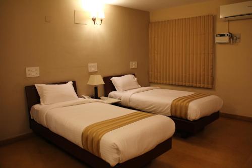 a hotel room with two beds and a window at Hanu Reddy Residences Wallace Garden in Chennai