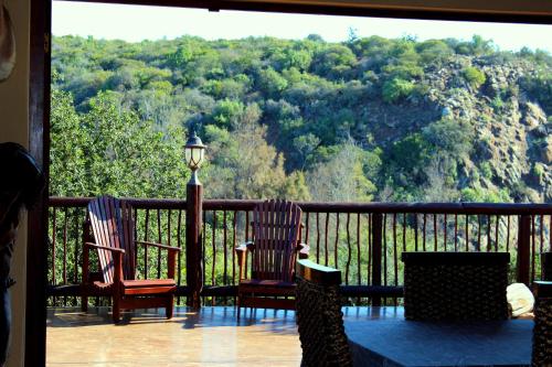 two chairs on a balcony with a view of a mountain at Valley Bushveld Country Lodge in Addo