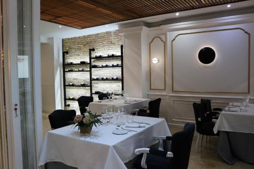 restauracja z białymi stołami, krzesłami i stojakami na wina w obiekcie Hotel Los Habaneros w mieście Cartagena
