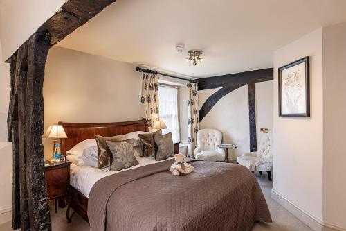 a bedroom with a large bed with a teddy bear sitting on it at The Castle Inn in Castle Combe