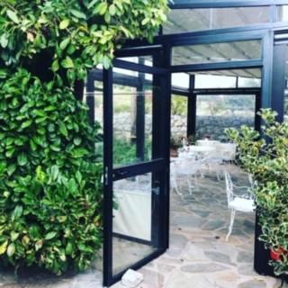 a glass door in a garden with a table and chairs at L'Acqua Viva in Calacuccia