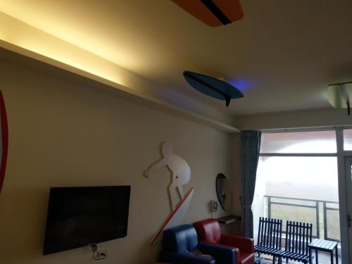 a living room with a flat screen tv and a couch at Happy Cape 玩皮城堡 in Huxi