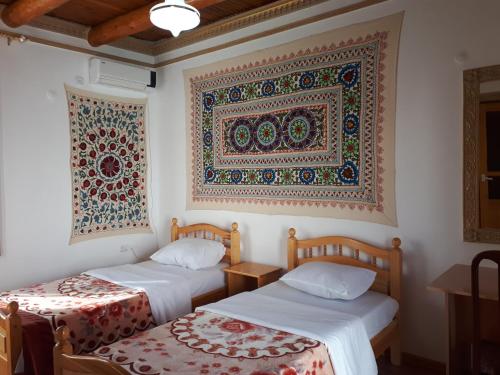 two beds in a room with a tapestry on the wall at Samani Bukhara in Bukhara