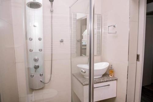 a white bathroom with a sink and a shower at 61 Cabanas in Durban