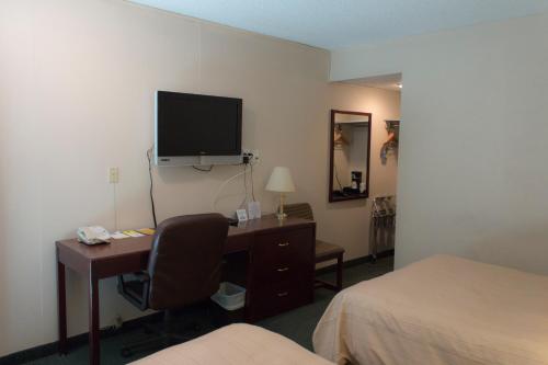 a hotel room with a desk and a television on the wall at Days Inn by Wyndham Lethbridge in Lethbridge