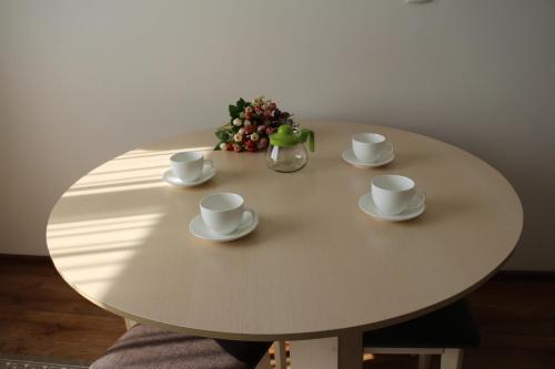 a table with cups and saucers and a vase on it at Апарт отель Welcome in Taldykorgan