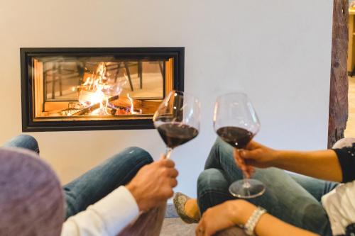 two people holding wine glasses in front of a fireplace at feldthurnerhof vinum-natur-relax in Feldthurns