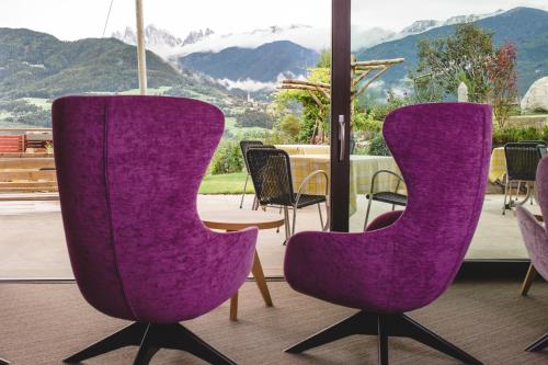 two purple chairs in front of a table and mountains at feldthurnerhof vinum-natur-relax in Feldthurns