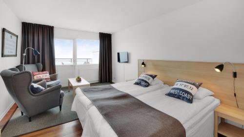 um quarto de hotel com uma cama grande e uma cadeira em Strand Hotell Borgholm em Borgholm