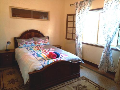 a bedroom with a bed with colorful pillows and a window at Chalet de la montagne in Ifrane