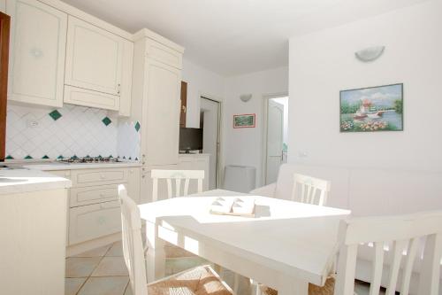 a white kitchen with a white table and chairs at Residence La Marmorata in Santa Teresa Gallura
