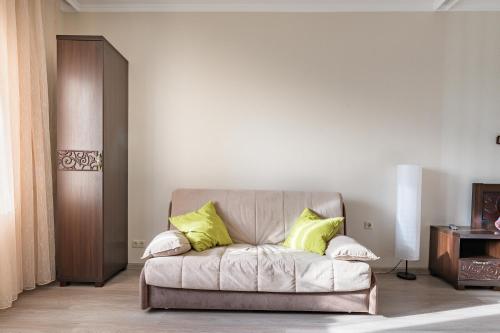 ein Wohnzimmer mit einem Sofa und zwei gelben Kissen in der Unterkunft Ваша Зона Комфорта на Колпакова 29 in Mytischtschi