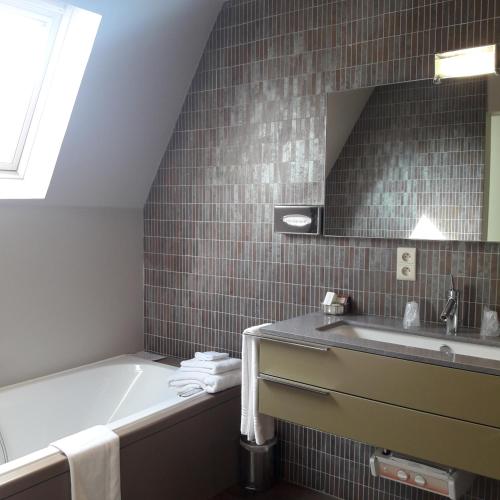 a bathroom with a tub and a sink and a mirror at Hotel Recour in Poperinge