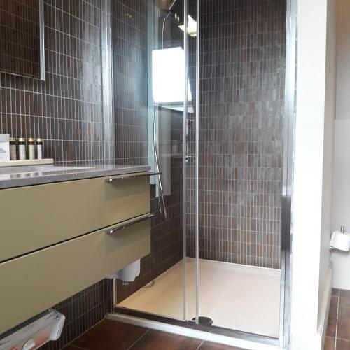 a shower with a glass door in a bathroom at Hotel Recour in Poperinge