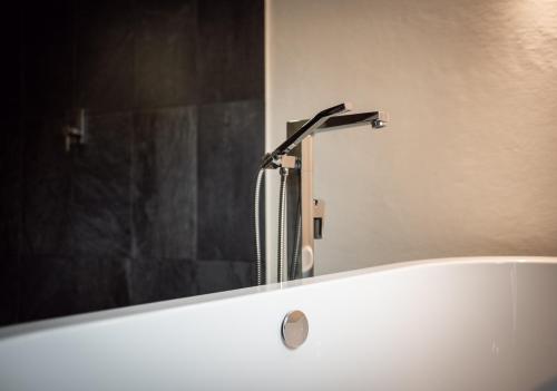 a bath tub with a shower head in a bathroom at Chalet Jagdhof in Sankt Johann im Pongau