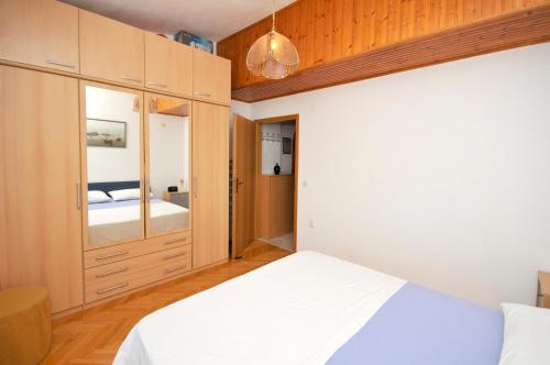 sypialnia z białym łóżkiem i drewnianymi szafkami w obiekcie Apartman Elena w Trogirze