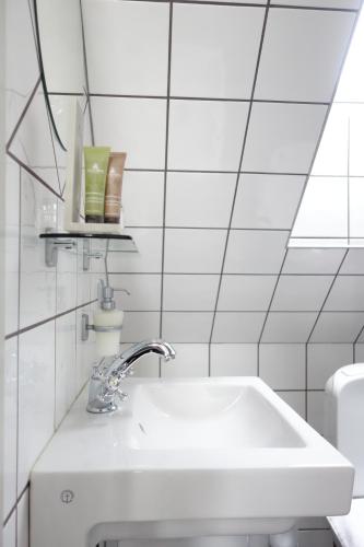 a white sink in a white tiled bathroom at Flädie Mat & Vingård in Flädie