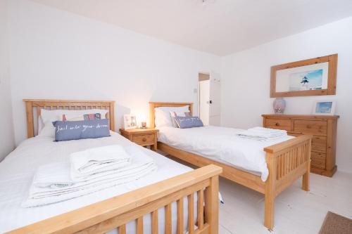 2 Betten in einem Zimmer mit Holzmöbeln in der Unterkunft Puddleduck Cottage in Aldeburgh