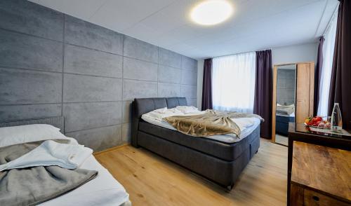a bedroom with two beds and a concrete wall at Hotel Giamas in Straubing