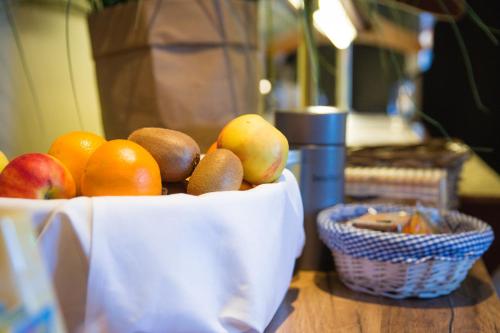 a bowl of fruit on a table with a basket of apples and oranges at Bed & Breakfast Van Marion in Oostvoorne