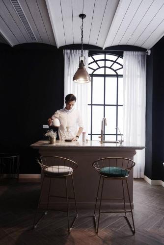 a woman standing at a kitchen counter with two chairs at 太太的小公館 入住須滿13歲以上 in Taitung City